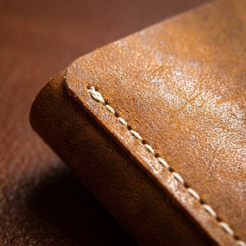 Macro detail of The Drifter: the burnished edge, white contrast saddle stitching and distressed tan Crazy Horse grain