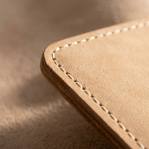 Macro detail of The Ledger: the burnished edge, cream saddle stitching and pale undyed natural nubuck
